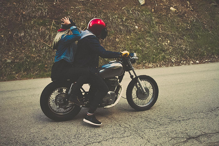 A man and woman riding together on a small cruiser