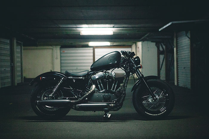 A black Harley-Davidson cruiser sits in an empty, dimly lit garage