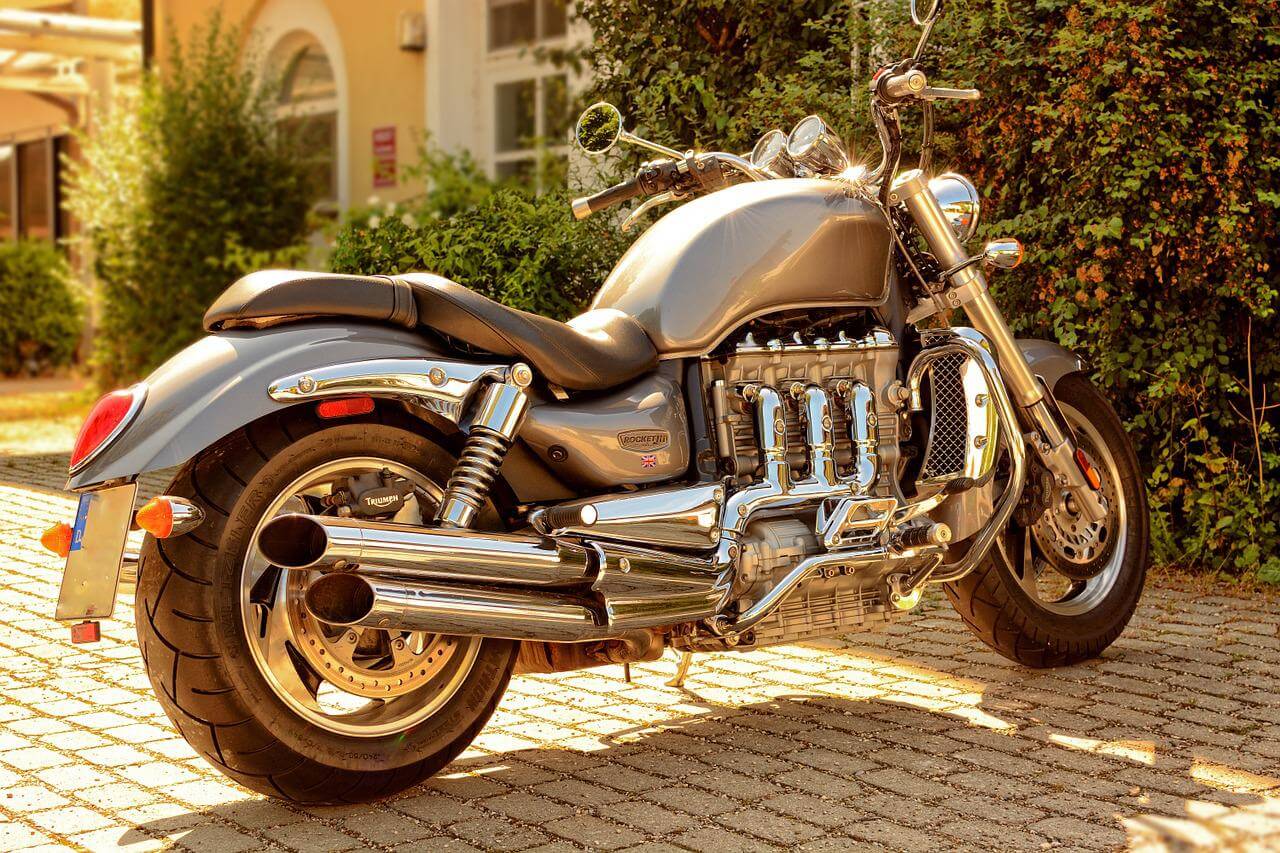 Chrome motorcycle in a driveway being hit by a lot of sunlight