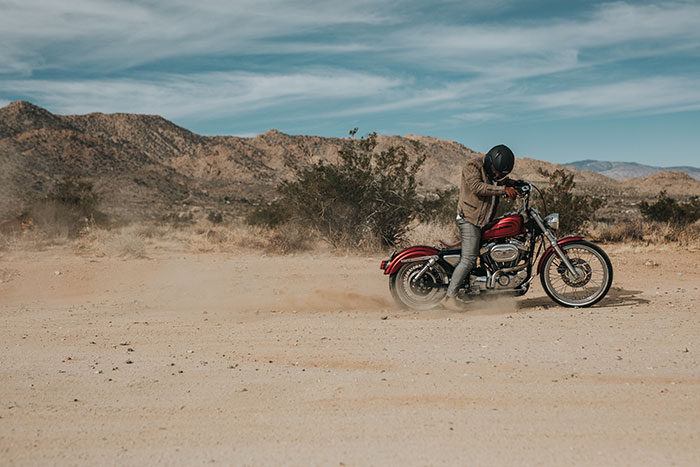 A man on a red cruiser experiements with the throttle on loose dirt