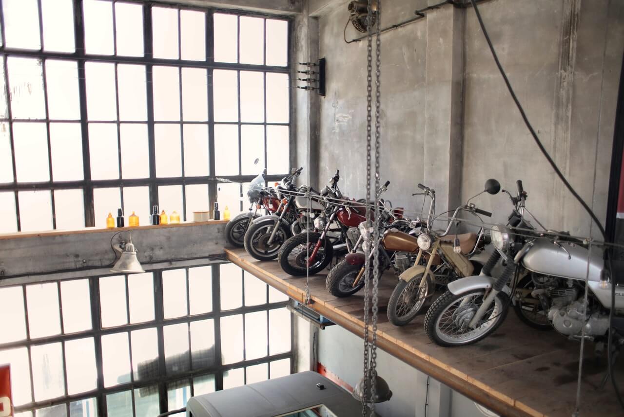 Several motorcycles on a platform in a large loft with large windows