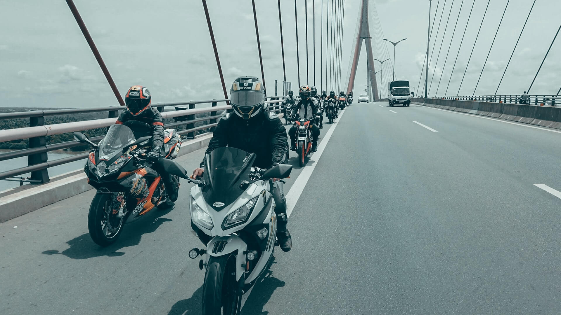 Large group of motorcyclists driving across a bridge