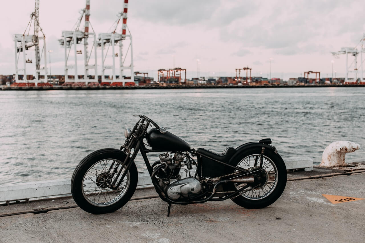 Parked retro motorbike by the water