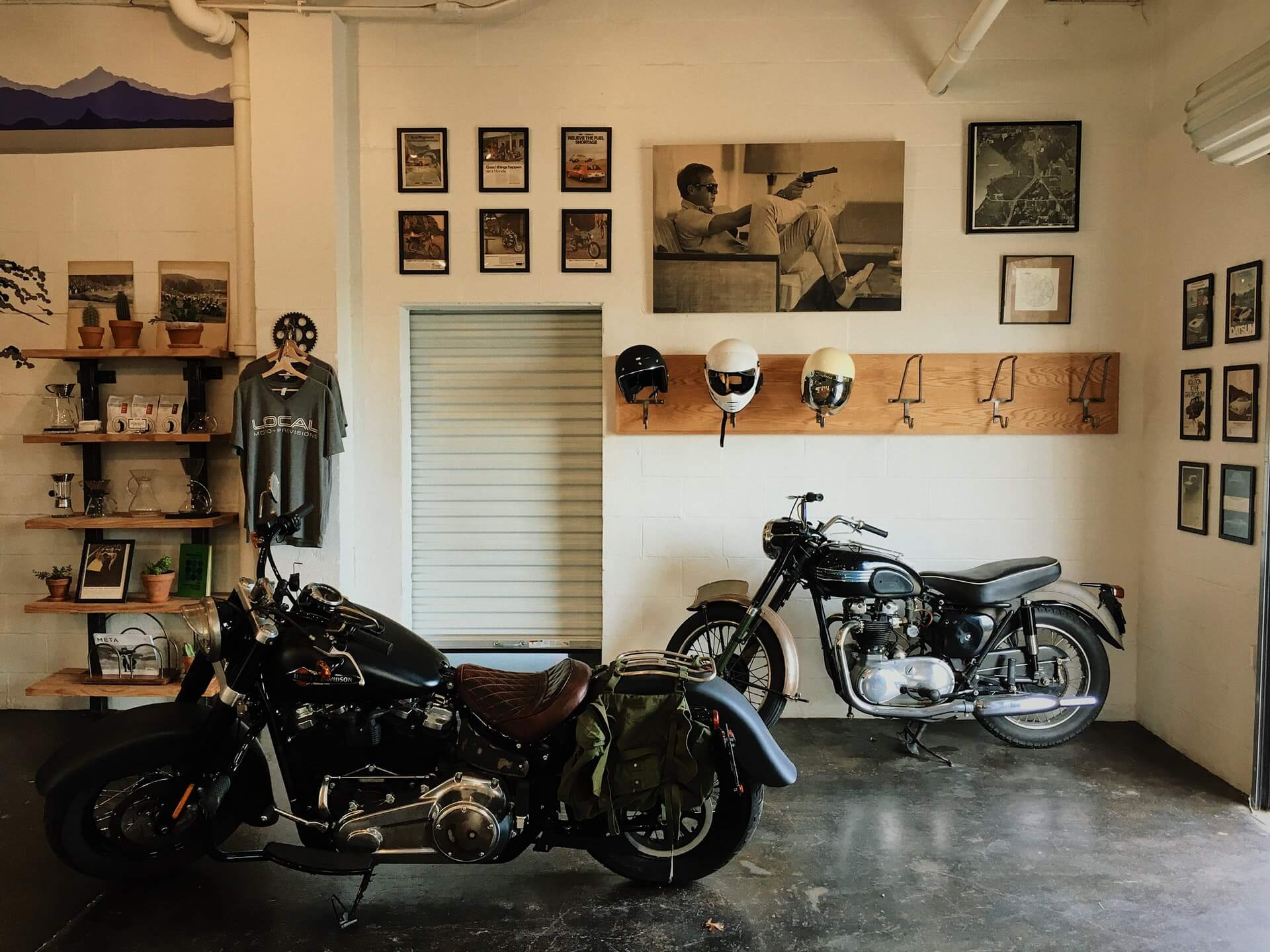 Two motorcycles in a room with shelves and framed pictures